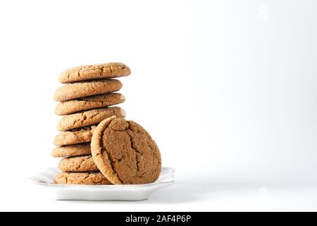 A gingerbread cookie s'appuie sur une pile sur les cookies sur une plaque blanche isolé sur un fond blanc ; copie de l'espace sur la droite Banque D'Images