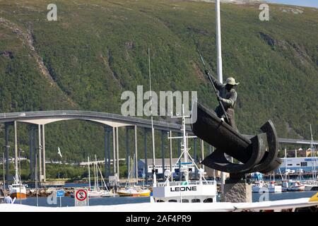 TROMSØ, NORVÈGE - Le chasseur de l'Arctique monument à port. Fangstmonument par Sivert Donali. Dans un bateau baleinier avec harpon. à distance, pont de Tromsø cro Banque D'Images