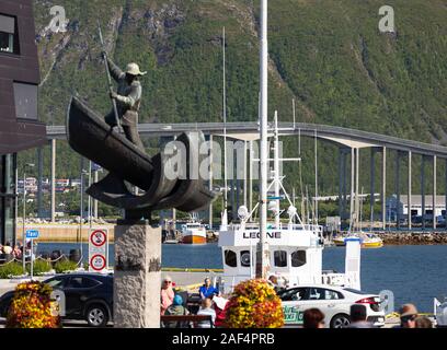TROMSØ, NORVÈGE - Le chasseur de l'Arctique monument à port. Fangstmonument par Sivert Donali. Dans un bateau baleinier avec harpon. à distance, pont de Tromsø cro Banque D'Images