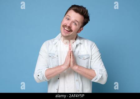 Alimenté homme heureux avec moustache holding paumes ensemble plus de poitrine en geste namaste bouddhiste salutation amis. Studio shot Banque D'Images