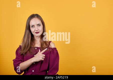 Jeune femme blouse en bourgogne sur mur orange isolé face à droite Banque D'Images