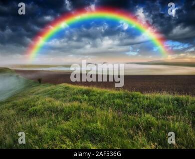 Dans le domaine de l'arc-en-ciel ciel pittoresque. sur un terrain vallonné après un orage. Banque D'Images