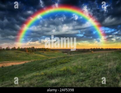 Dans le domaine de l'arc-en-ciel ciel pittoresque. sur un terrain vallonné après un orage. Banque D'Images