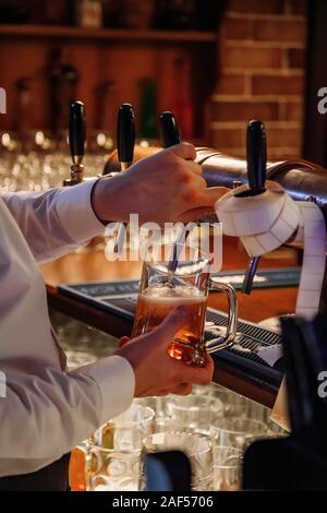 Bartender pouring Projet de la bière à partir de la grue dans le verre dans un pub. Banque D'Images