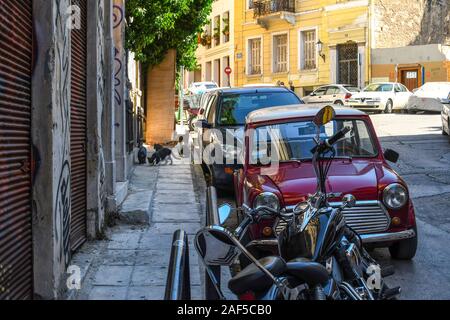 Un groupe de chats sort d'une attente dans un mur sur un trottoir dans la région de Plaka d'Athènes, Grèce. Banque D'Images