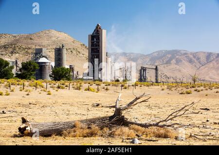 Une cimenterie à Tehachapi Pass, Californie USA, avec la sécheresse a tué les arbres en premier plan. La production de ciment est l'un des plus avides de carbone l'indu Banque D'Images