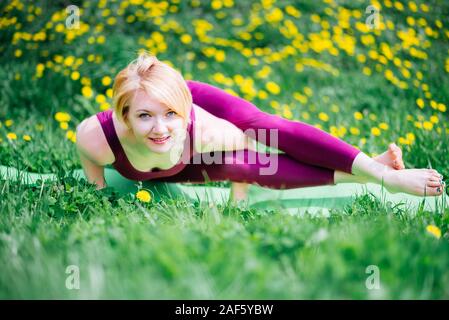 Belle fille engagée dans le yoga on Green grass on a sunny day Banque D'Images