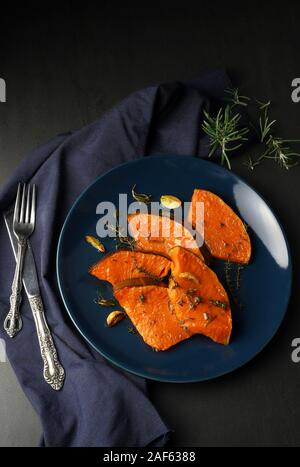 Des plats traditionnels de citrouille d'automne. Vue de dessus les tranches de citrouille rôties aux épices, l'huile d'olive, des herbes sur fond sombre. Banque D'Images