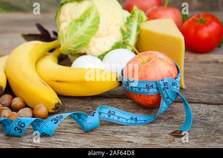 Les fruits et légumes, ruban à mesurer sur le vieux fond de bois. Concept de la nutrition appropriée. Banque D'Images