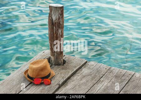 Chapeau de paille et lunettes de soleil sur la jetée en bois Banque D'Images