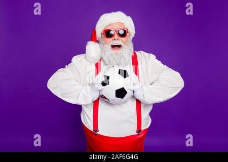 Photo de grey haired santa père holding football ball passer nouvel an nuit à regarder la finale de ligue de champion enthousiaste porter costume specs sun Banque D'Images