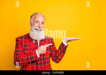 Photo de grand-père cool avec barbe blanche holding ouvrez palm indiquant l'usure produit nouveauté doigt rouge à carreaux costume cravate blazer couleur jaune isolé Banque D'Images