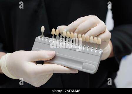 Le médecin tient dans sa main des tests pour les dents du patient avant le blanchiment Banque D'Images