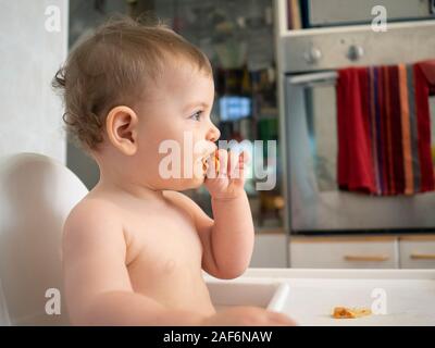 1 ans bébé est assis sur une chaise haute en attente de son repas Banque D'Images