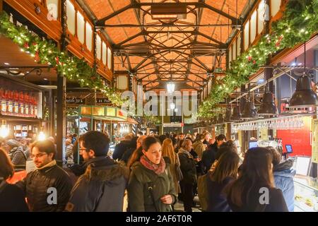 Mercado San Miguel de Madrid, Espagne est occupé avec les gens. Un marché couvert qu'on voit ici en décembre avec des guirlandes de Noël décorant les poutres apparentes. Banque D'Images