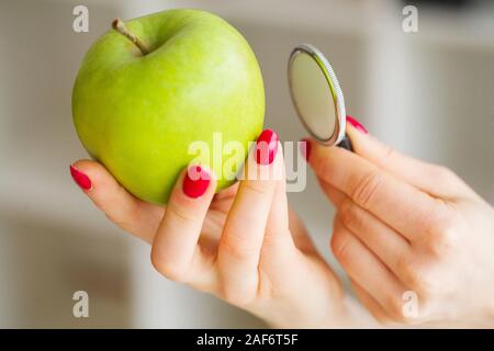 La santé. L'alimentation saine. La nutritionniste tient dans les mains de frais vert pomme. Les fruits et légumes frais sur la table. Heureux Médecin. Haut Banque D'Images