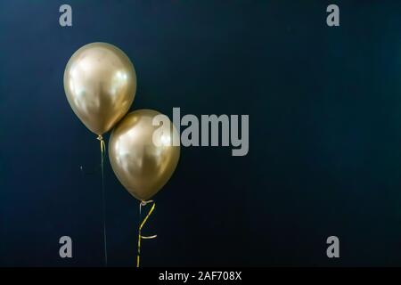 Deux ballons d'or sur un fond sombre. Concept de vacances, carte postale Banque D'Images