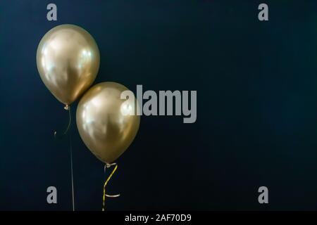 Deux ballons d'or sur un fond sombre. Concept de vacances, carte postale Banque D'Images