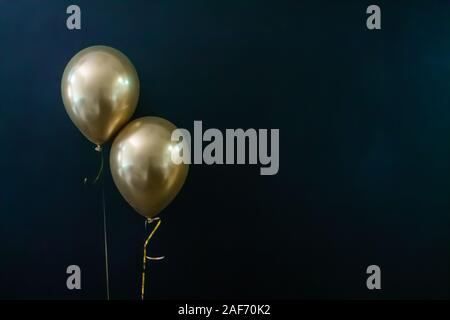 Deux ballons d'or sur un fond sombre. Concept de vacances, carte postale Banque D'Images