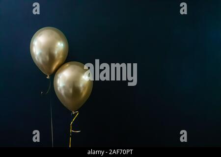 Deux ballons d'or sur un fond sombre. Concept de vacances, carte postale Banque D'Images