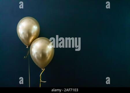 Deux ballons d'or sur un fond sombre. Concept de vacances, carte postale Banque D'Images