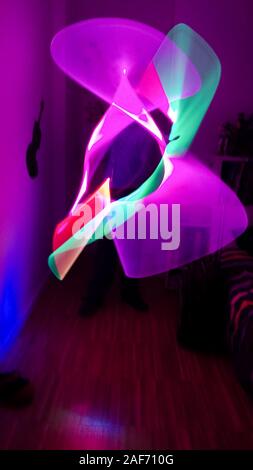 Garçon jouant dans sa chambre avec un sabre laser en différentes couleurs. Effet Lightpainting Banque D'Images