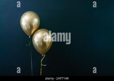 Deux ballons d'or sur un fond sombre. Concept de vacances, carte postale Banque D'Images