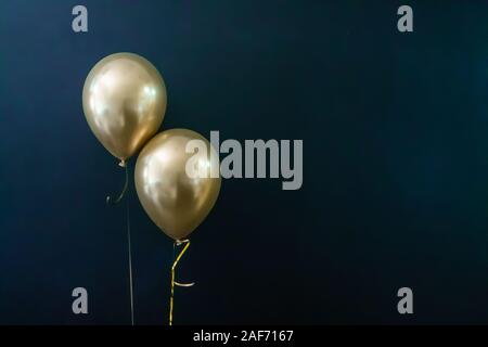 Deux ballons d'or sur un fond sombre. Concept de vacances, carte postale Banque D'Images