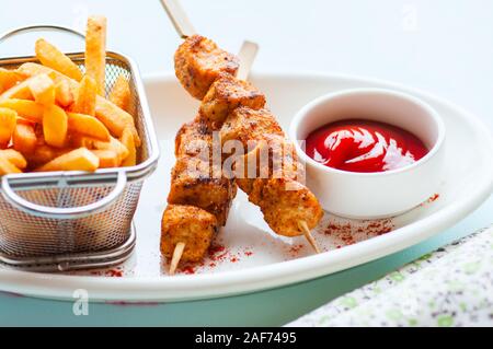 Brochettes de poulet cuit dans une assiette avec des pommes de terre frites et ketchup. Close up. Banque D'Images