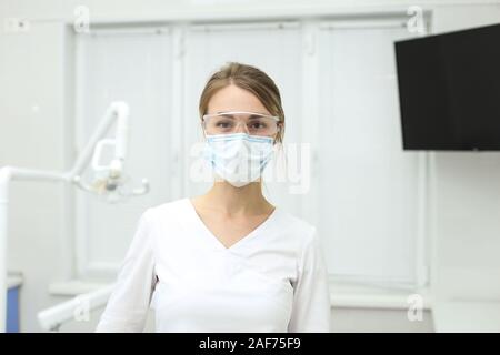 Dentiste souriant se tient au milieu de l'armoire avec son masque jusqu'pullded. Focus sélectif. Banque D'Images