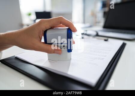 Close-up of personne mains appuyant sur Stamper sur le document Banque D'Images