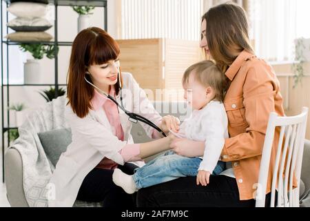 Pleurer bébé fille enfant malade sur les mains de la mère à l'hôpital ou à la maison, et la femme médecin généraliste ayant l'examen. Banque D'Images