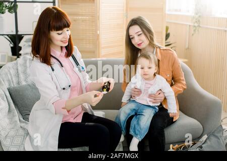 Petite fille accepte de boire le sirop de la médecine avec cuillère de médecin de famille à la maison Banque D'Images