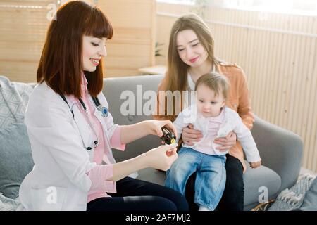 Petite fille accepte de boire le sirop de la médecine avec cuillère de médecin de famille à la maison Banque D'Images