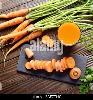 Vue de dessus au jus de carotte bio végétarienne fraîche sur une table de cuisine en bois Banque D'Images