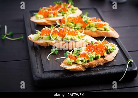 Sandwiches au saumon caviar rouge et salsa à l'avocat. Sandwich pour le déjeuner. La nourriture délicieuse. Banque D'Images