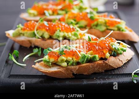 Sandwiches au saumon caviar rouge et salsa à l'avocat. Sandwich pour le déjeuner. La nourriture délicieuse. Banque D'Images