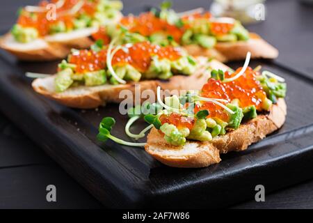 Sandwiches au saumon caviar rouge et salsa à l'avocat. Sandwich pour le déjeuner. La nourriture délicieuse. Banque D'Images