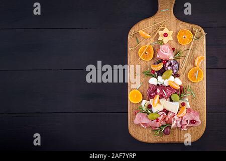 L'antipasto platter avec jambon, jambon, salami, fromage et olives sur un fond de bois. Table de Noël. Vue de dessus, les frais généraux Banque D'Images