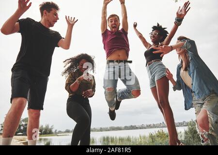 Célébrer lors d'un saut. Groupe de personnes a pique-nique sur la plage. Les amis de s'amuser à l'heure de fin de semaine