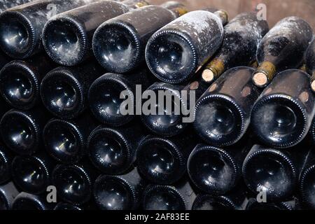 Des piles de bouteilles de vin dans des casiers à plat dans la vieille cave à vin ou cave. Vault Concept avec de vieux vins rares, collection exclusive. Des bouteilles de vin antique Banque D'Images