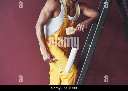 Outils dans les mains. Young african american travailleur dans l'uniforme jaune ont un emploi Banque D'Images