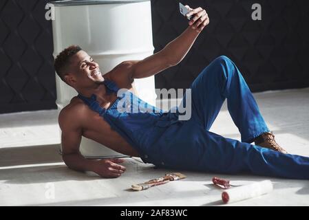 En tenant lieu de travail sur selfies. Young african american gars en uniforme bleu ont une pause sur son travail Banque D'Images