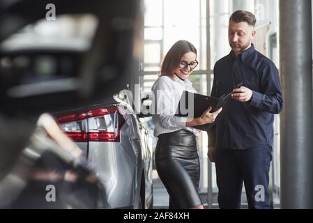 L'utilisation de documents. Assistant-gérant de donner des conseils et l'aide au client dans le salon de l'automobile Banque D'Images