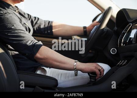 Main sur l'interrupteur de vitesse stick. Conducteur se sent bien dans sa toute nouvelle voiture. Équitation à sunny day Banque D'Images