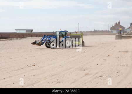 Un tracteur tractant un râteau de surf pour nettoyer les débris d'une plage publique à Roker, Sunderland Banque D'Images