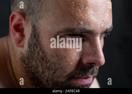 Portrait d'un beau jeune homme transpiration sur fond sombre Banque D'Images
