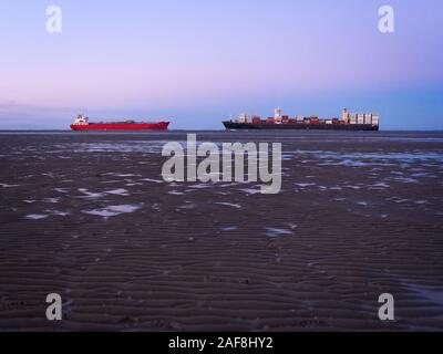 Deux navires passant l'embouchure de la rivière Elb dans différentes directions près de Otterndorf à marée basse de la mer des Wadden en face d'un merveilleux sk pastel Banque D'Images