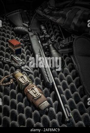 Vis moderne carabine de petit calibre .22Lr sur un fond sombre. Un fusil à lunette de tir, cartouches pour elle et un couteau de chasse. Hunter kit. Banque D'Images
