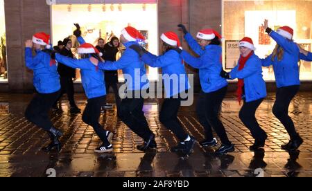 Le 13 décembre, 2019, Metro Bank ouvre une nouvelle succursale à Market Street, Manchester, Royaume-Uni. Personnel porte des chapeaux de Noël pour accueillir les clients. Un groupe d'employés en dehors de la danse et ne la conga pour attirer l'attention des passants - par. Banque D'Images